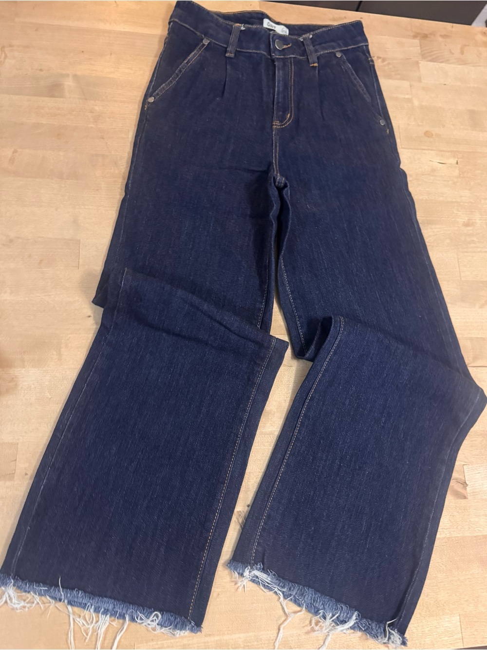 OAT New York high-rise pleated wide-leg jeans in a dark wash featuring a raw hem